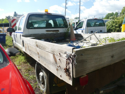 Ford F-250 Super Duty pickup truck rear/side view showing flatbed wooden bed and tailgate area.