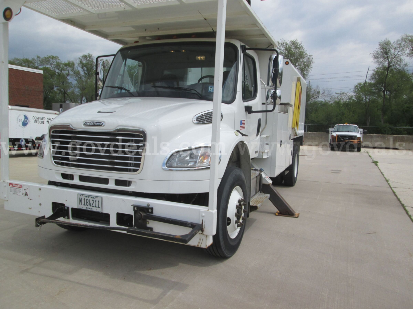 Freightliner M2 106 bucket truck with front cab and raised bucket platform, white paint, stock number 8943-89, California plate, parked outdoors.