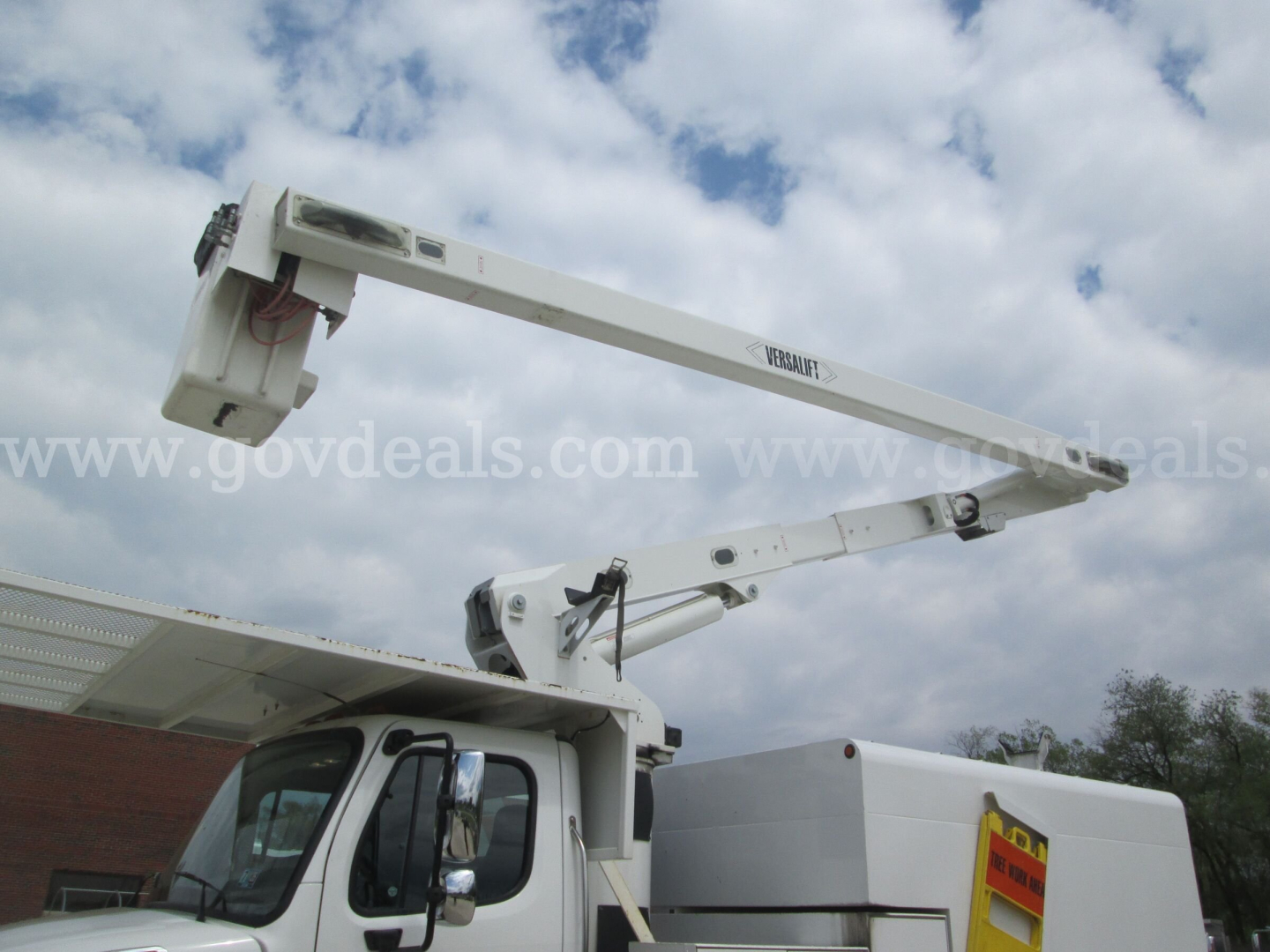 Freightliner bucket truck boom arm extended over cab showing platform and hydraulic arm components.
