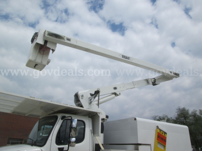 Freightliner bucket truck boom arm extended over cab showing platform and hydraulic arm components.
