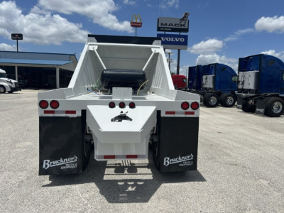 Trailer rear view showing white dump trailer with black mud flaps and Bruckners Equipment branding.