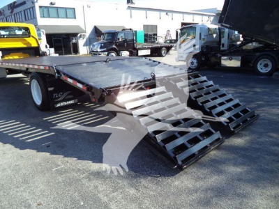 Flatbed tow truck with dual ramps and hydraulic lift showing loading deck and ramp stairs.