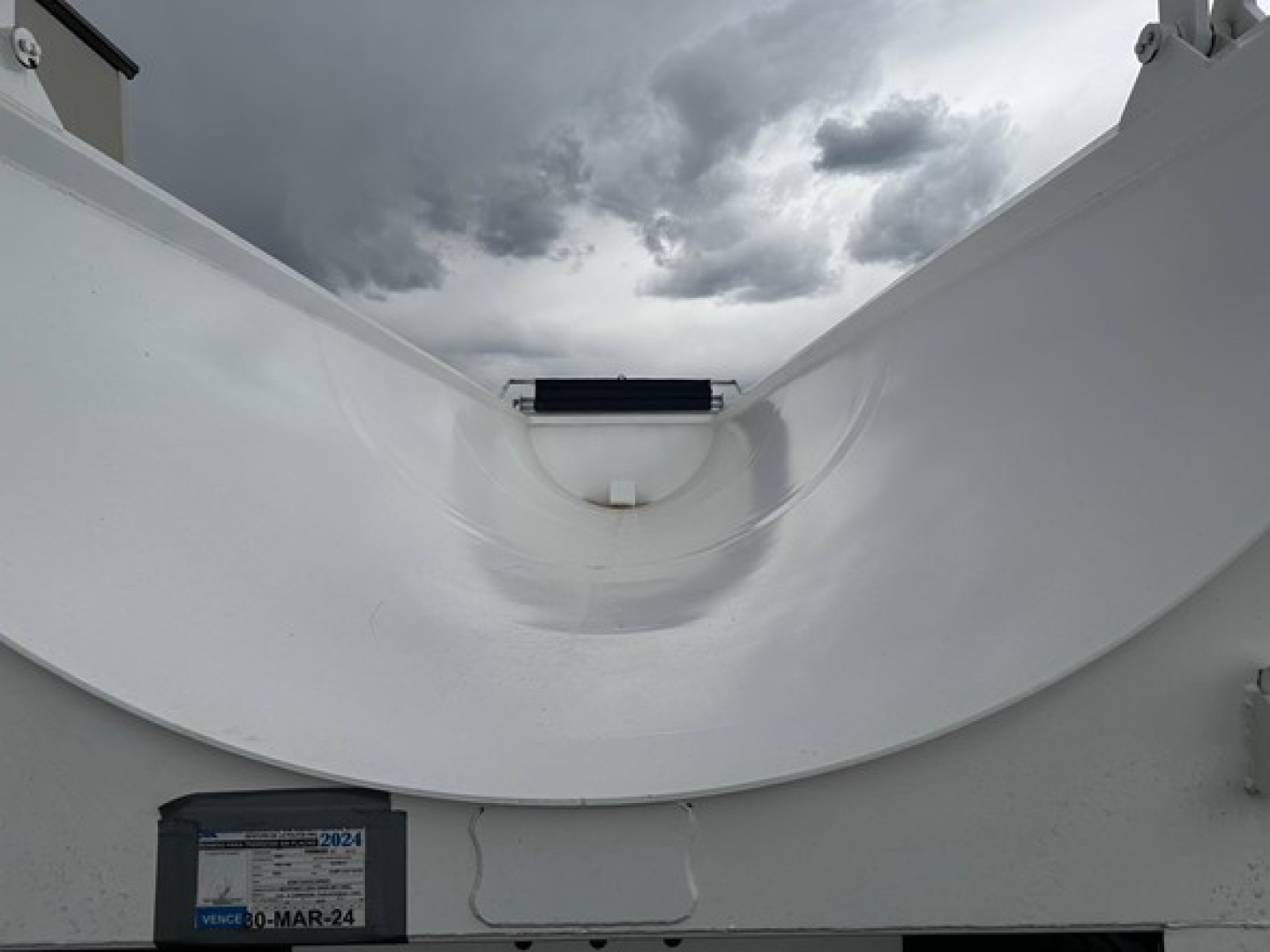 Dump trailer interior showing a white frameless 1/2 round rock end dump with curved hopper and open top edge.