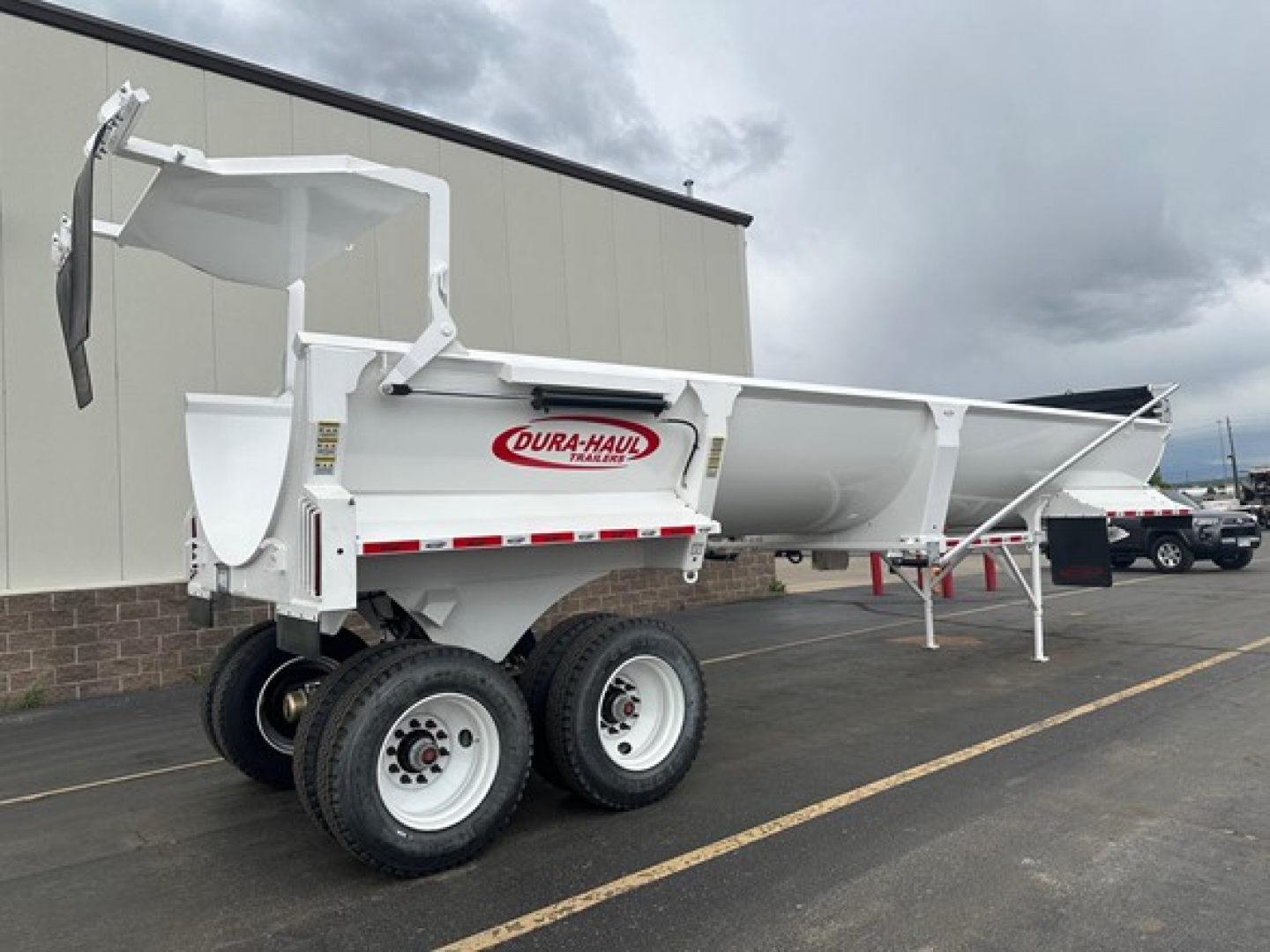 Dura-Haul Frameless 1/2 Round Rock End Dump trailer showing dual rear axles and white body with DURA-HAUL logo.