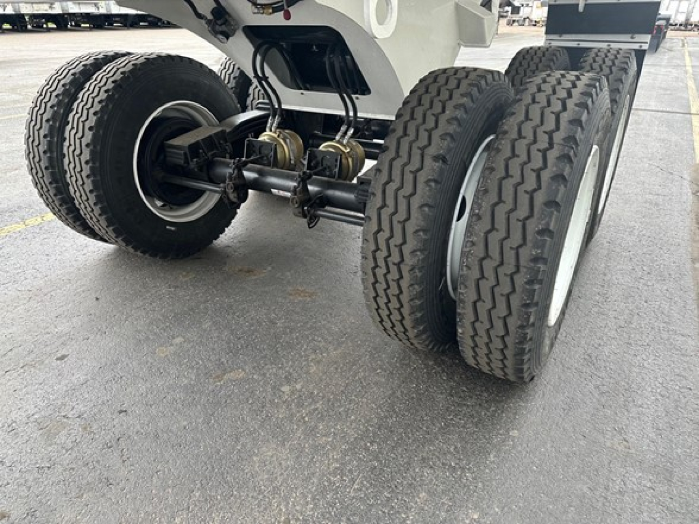 Trailer axle assembly with dual rear axles and heavy-duty suspension visible.
