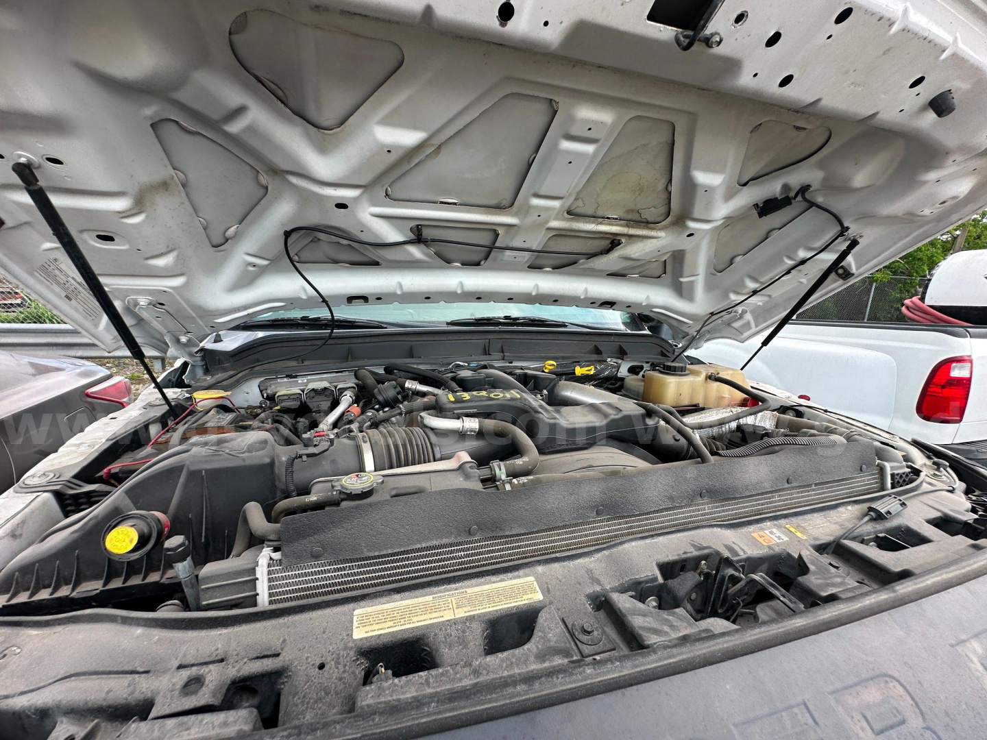Ford F-350 engine bay under open hood with visible V8 components and fluid reservoirs.
