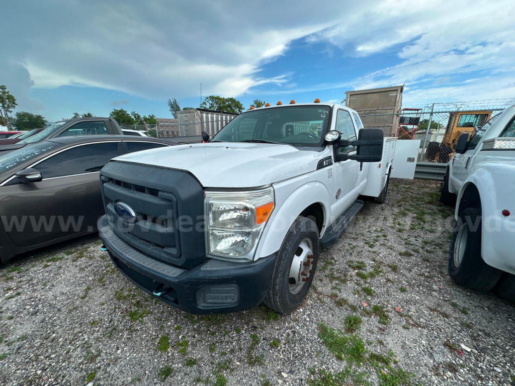 Ford F-350 utility truck in a parking lot showing front grille, headlights, and side mirrors; white body with black bumper and dual rear wheels.