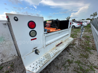 Ford F-350 service/utility truck bed showing pump and mounting hardware with controls and exhaust system visible.