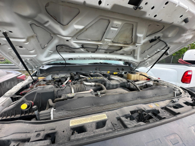 Ford F-350 engine bay under open hood with visible V8 components and fluid reservoirs.