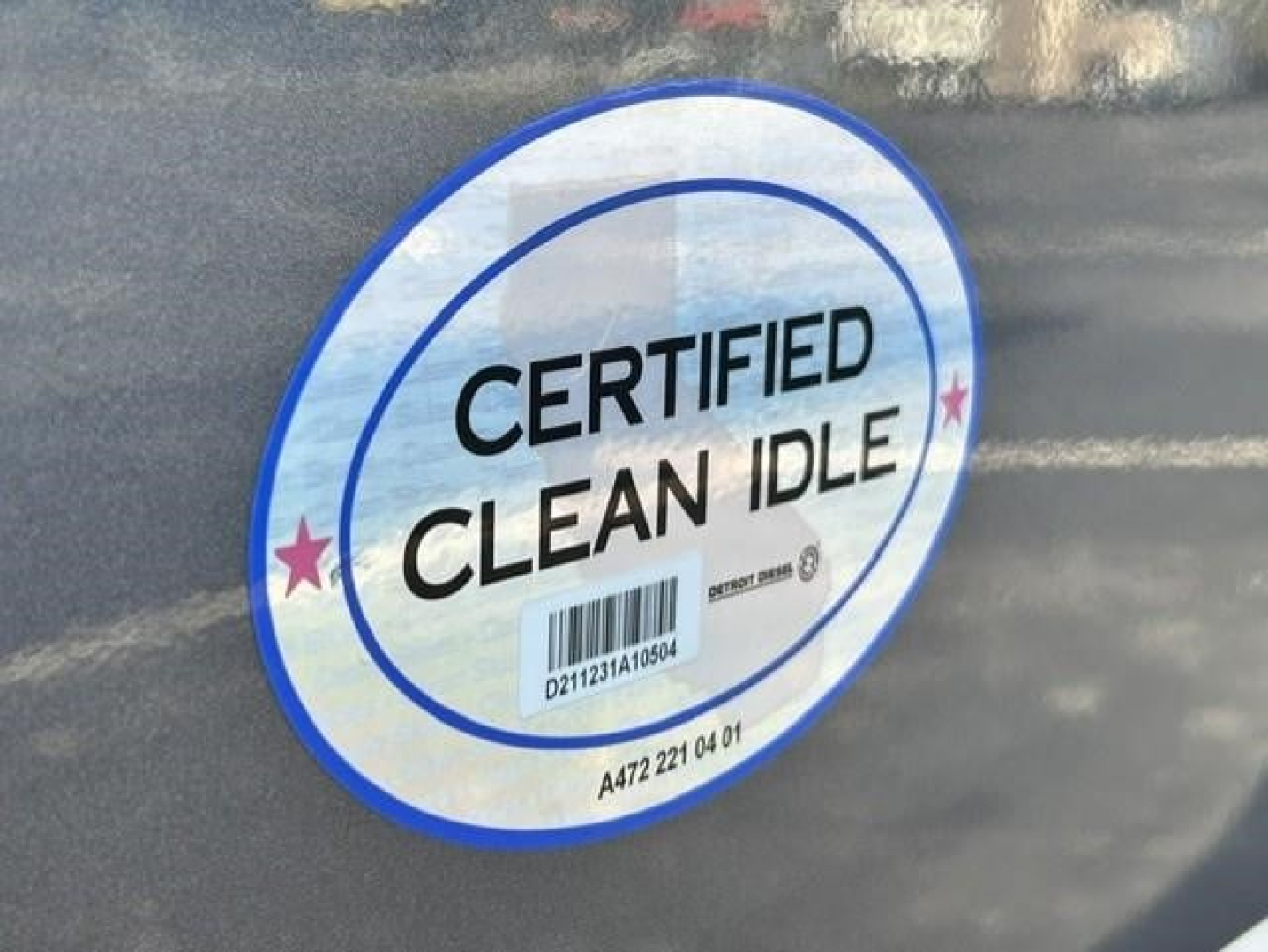Circular sticker on Freightliner Cascadia showing CERTIFIED CLEAN IDLE with barcode and small stars.