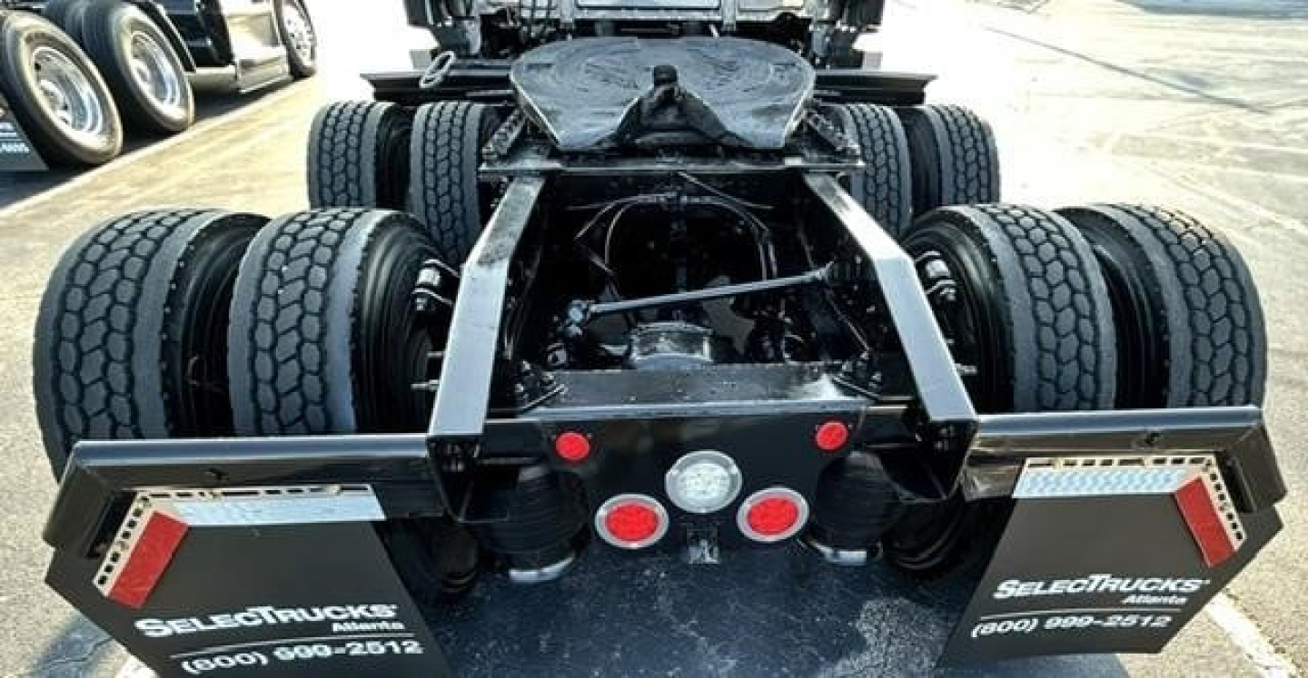 Truck chassis rear view showing dual rear axles and mud flaps with SelecTrucks branding.