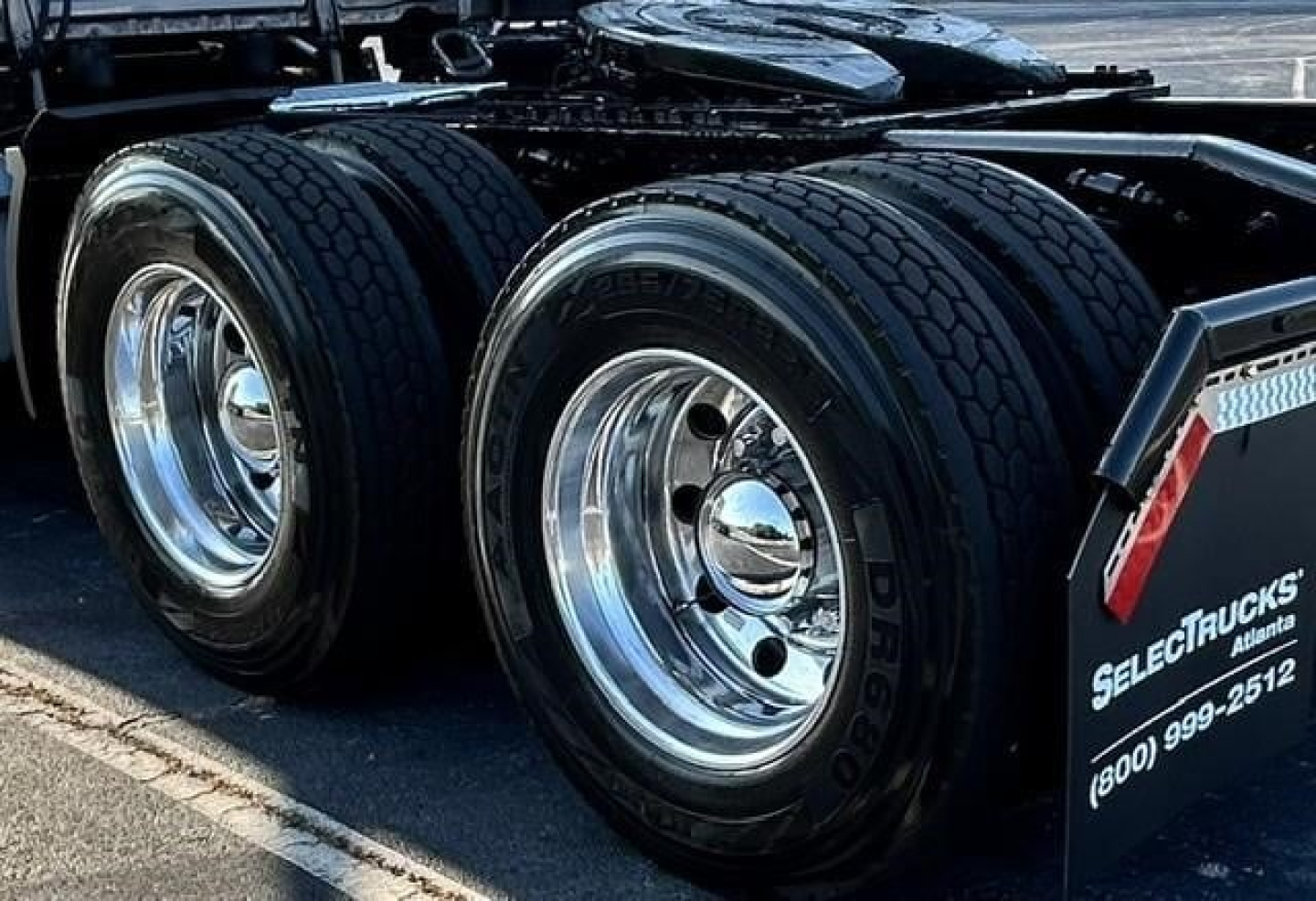 Freightliner Cascadia 126 tractor-trailer rear dual axles with polished chrome wheels and black tires.