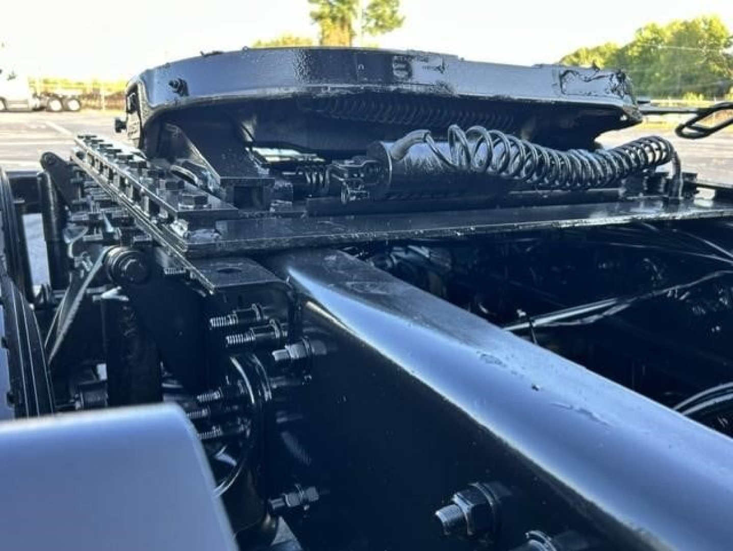 Freightliner Cascadia truck chassis view showing heavy-duty framing and hydraulic lines. Visible components include a large frame rail, air hoses, and linkages.