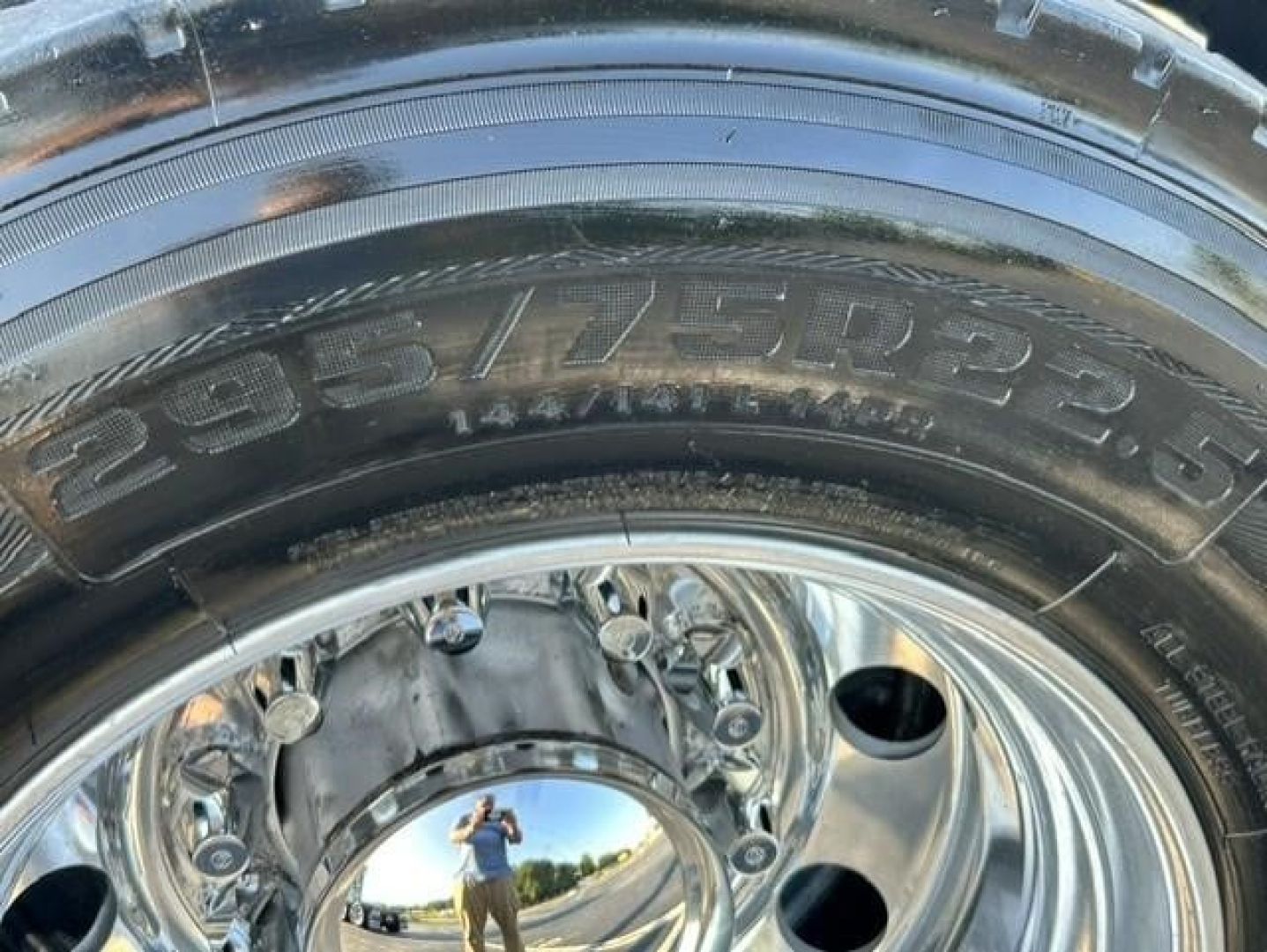 Tire and polished wheel close-up on a Freightliner Cascadia truck showing large tire with visible sidewall markings and chrome hub.