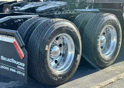 Freightliner Cascadia truck rear dual rear wheels showing tires and chrome rims, with SelectTrucks Atlanta mudflap and contact number.
