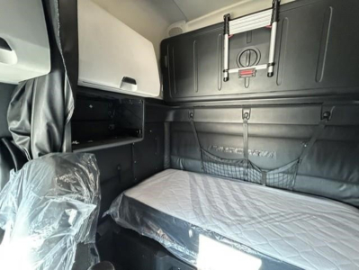 Truck sleeper cab interior showing bunk bed with protective plastic on seat and storage net, Freightliner Cascadia 126 interior