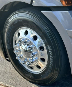 Truck wheel close-up showing Bridgestone tire on polished chrome hubcap of Freightliner Cascadia 126.