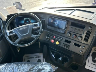 Freightliner Cascadia dash area showing steering wheel and dashboard with large central touchscreen display and control panel.