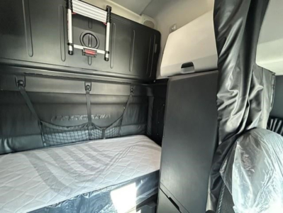 Cab interior of a Freightliner Cascadia sleeper showing bunk bed with mattress and storage panels.