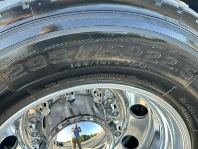 Tire and polished wheel close-up on a Freightliner Cascadia truck showing large tire with visible sidewall markings and chrome hub.