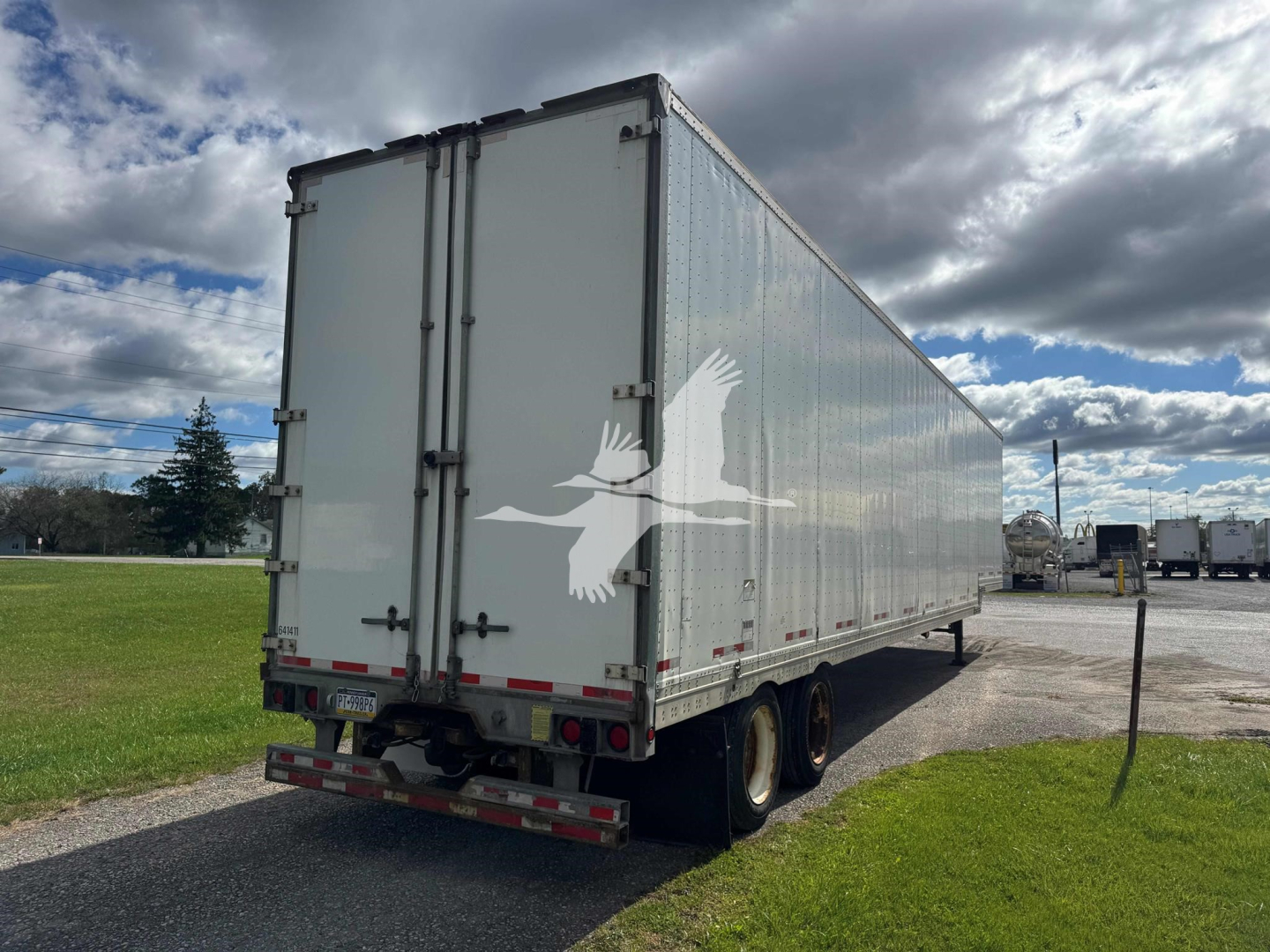 Manac drop van trailer with side and rear views, white exterior, dual rear wheels, and closed rear doors.