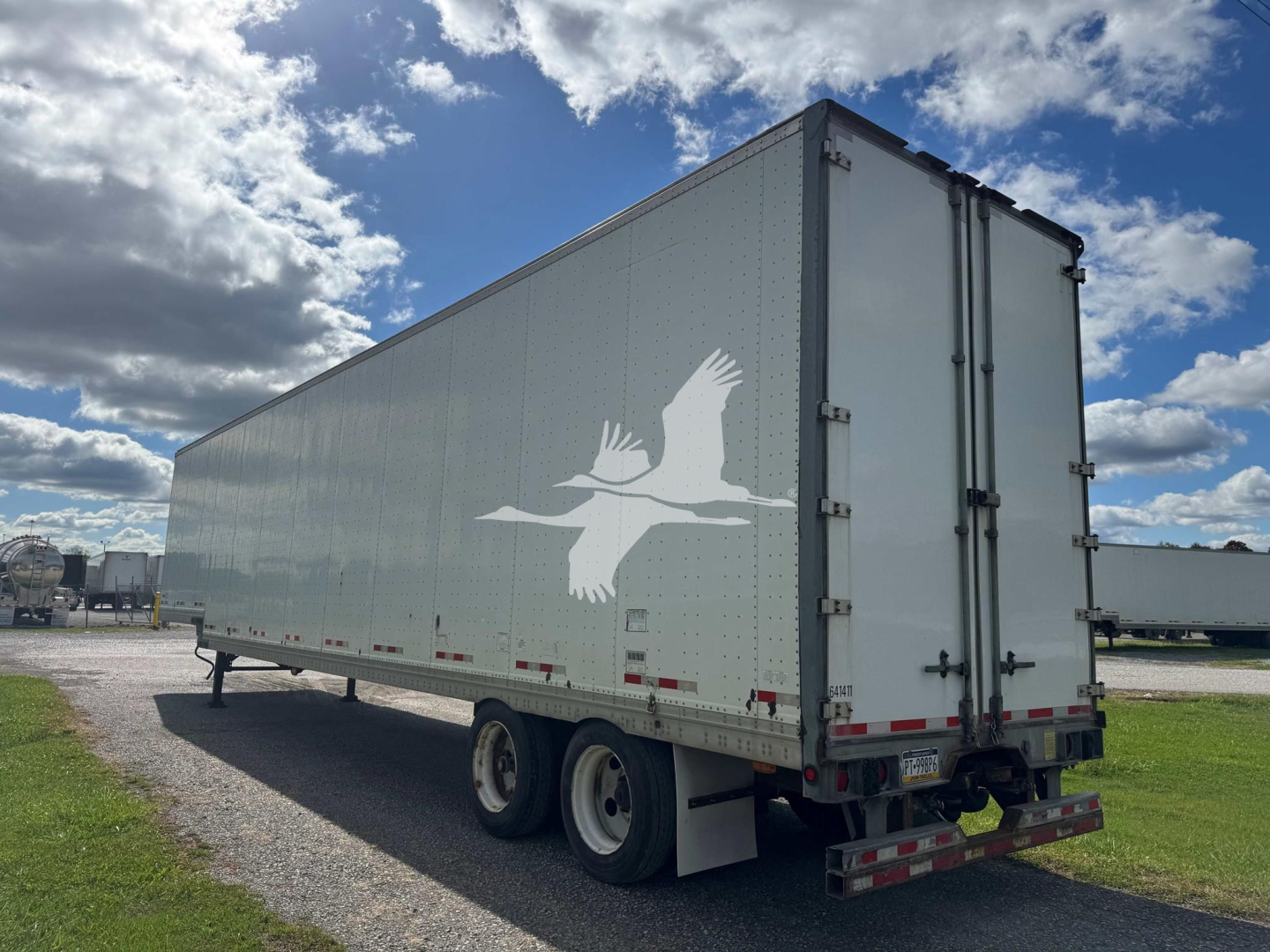 2015 Manac Drop Van trailer showing dual rear doors and white crane-like logos on light gray side panels.