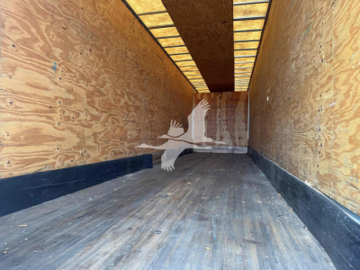 Interior of a 2015 Manac drop van trailer showing empty cargo area with plywood walls and a black floor.