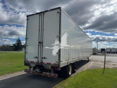 Manac drop van trailer with side and rear views, white exterior, dual rear wheels, and closed rear doors.