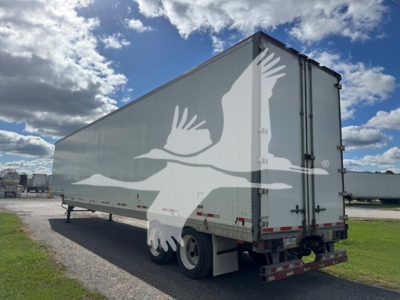 Manac drop van trailer showing side and rear views with a large white bird graphic on gray walls.