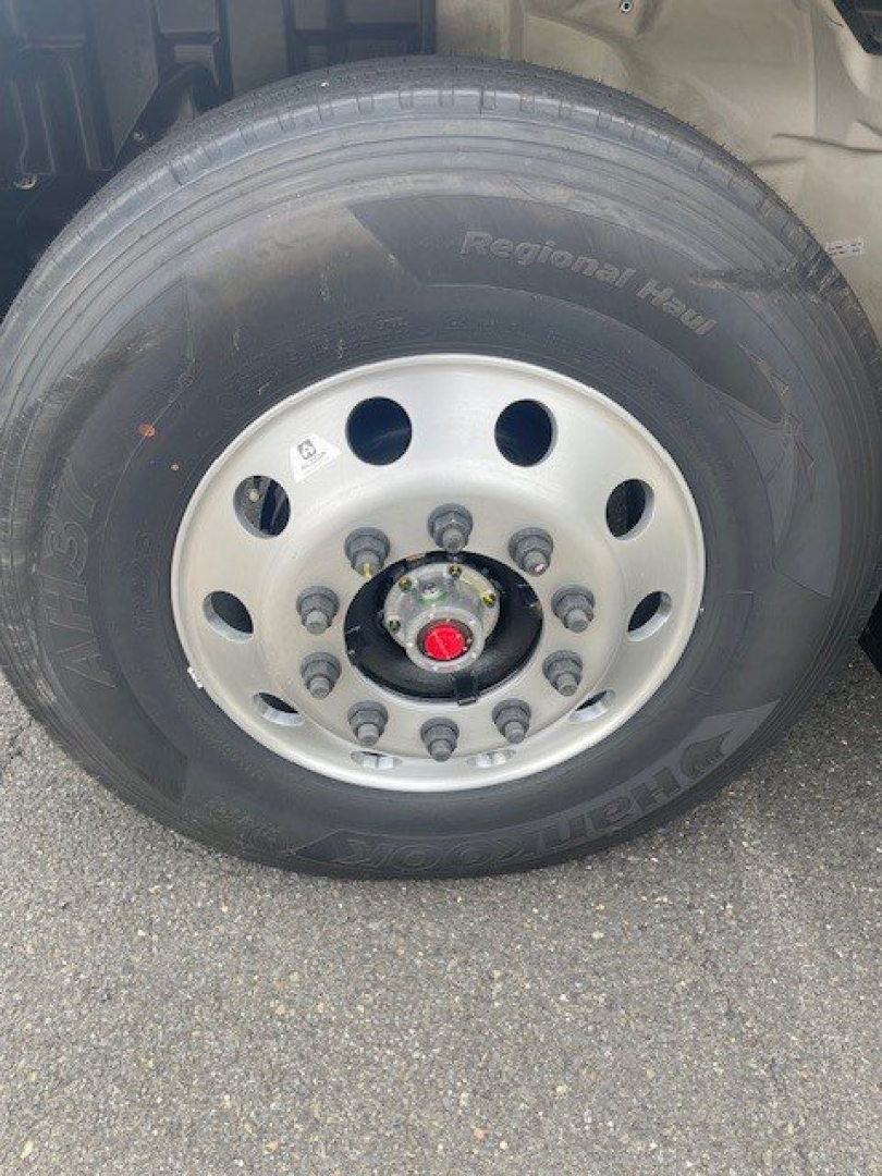 Truck wheel close-up showing a silver steel rim with multiple lug nuts and a red center cap, tire labeled 'Regional Haul' on the sidewall.