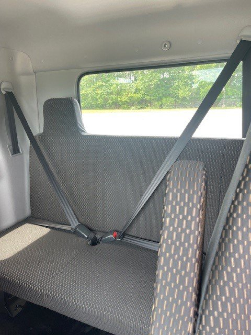 Cab chassis truck interior rear seating area with seat belts and window view; fabric seats with dotted pattern.