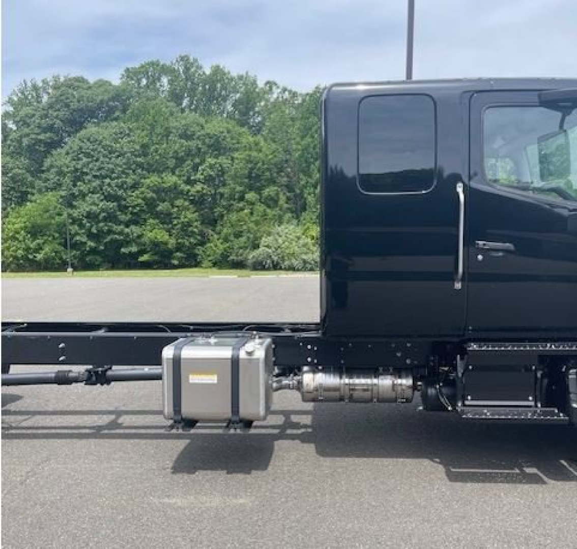 Truck cab chassis side view showing fuel tank and exhaust/bracket assembly along the frame.