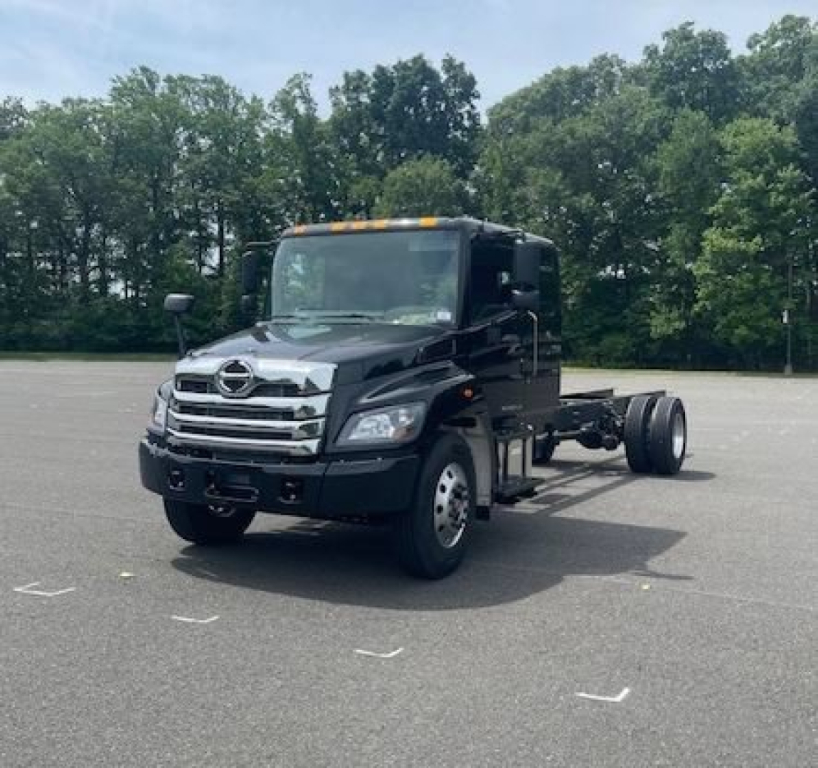Truck cab chassis showing front grille with Hino emblem and dual headlights, black cab, exposed rear chassis, VIN 5PVNV7ET0V5T50001 not visible on image
