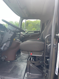 Cab interior of a 2027 Hino L7 truck showing driver's seat and dashboard with steering wheel. Visible text includes VIN 5PVNV7ET0V5T50001 on the listing, and stock details in the description region.