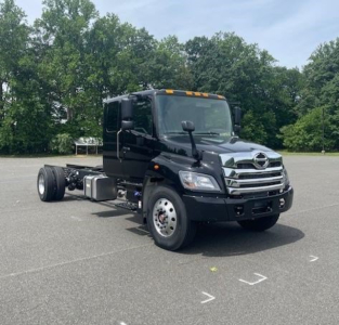 2027 Hino L7 cab chassis truck in view showing front and side profile with dual rear wheels and fuel tanks.