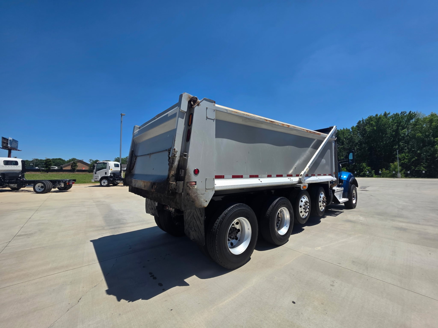 Kenworth T880S dump truck rear view showing dual rear wheels on a triple-axle setup and cargo bed raised slightly.