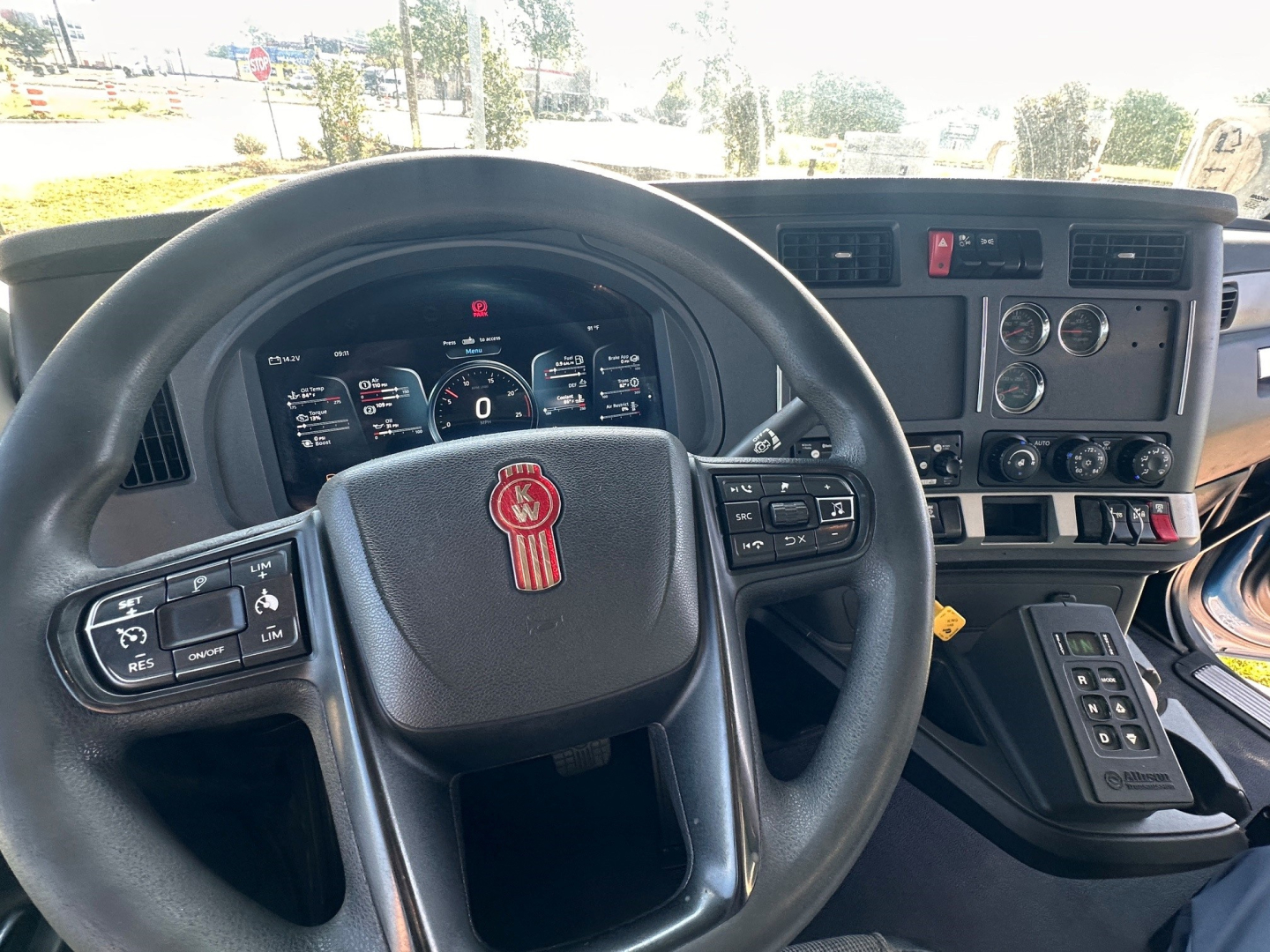 Kenworth T880S dashboard and steering wheel view showing instrument cluster, center console, and gear selector with controls.