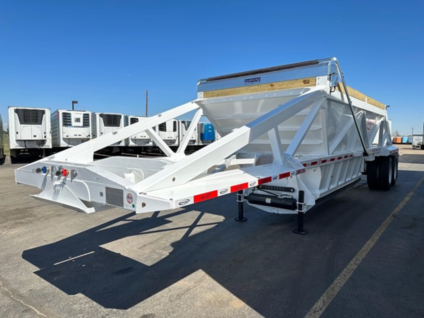 Trailer side view of a white 2026 Dura Haul Air Ride Bottom Dump with reinforced truss frame and hydraulic system, flatbed top, dual rear axles, and landing gear.
