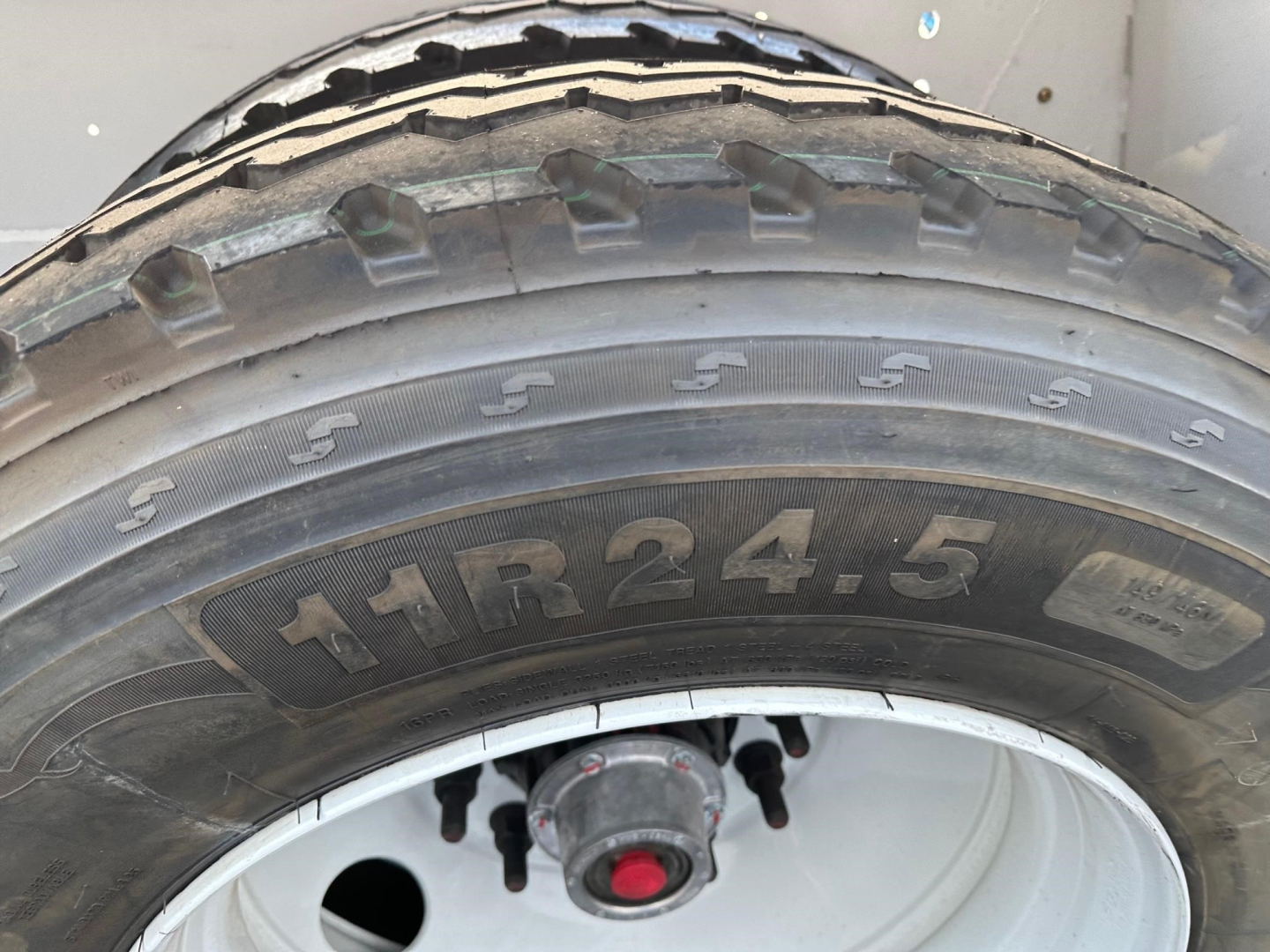 Truck trailer tire and wheel showing 11R24.5 tire size on a Dura Haul air ride bottom dump trailer.