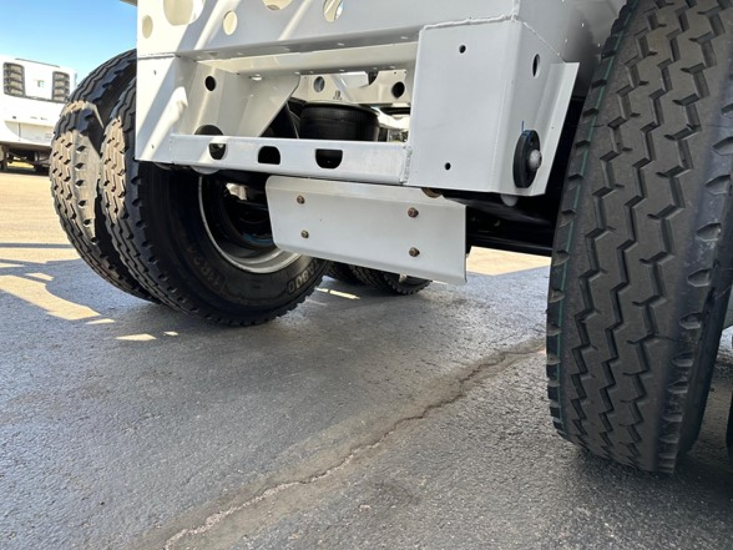 Rear view of a new Dura Haul air ride bottom dump trailer showing dual rear axles, tires, chassis, and underside components. No readable serials or labels in close view.