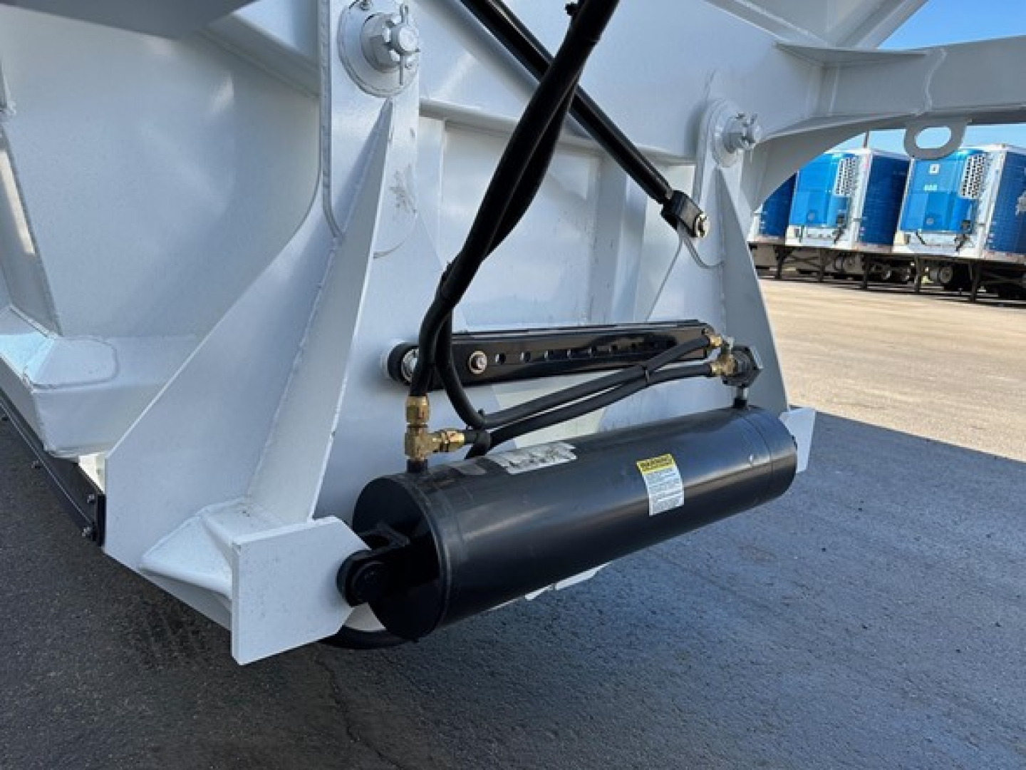 Bottom-dump trailer linkage and hydraulic cylinder visible on white Dura Haul air ride bottom dump trailer.