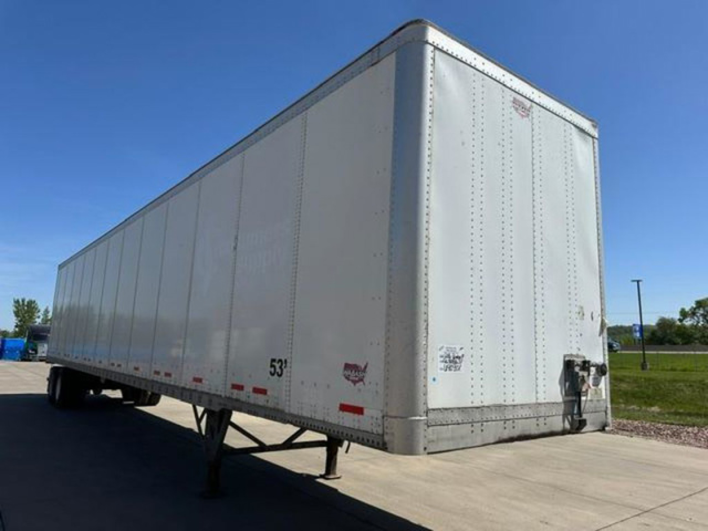 Trailer side view showing a 53' Wabash van trailer with riveted aluminum walls and landing gear, rear doors, and front hitch area.
