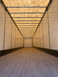 Trailer interior showing empty cargo area with wood floor, side walls and roof ribs visible.