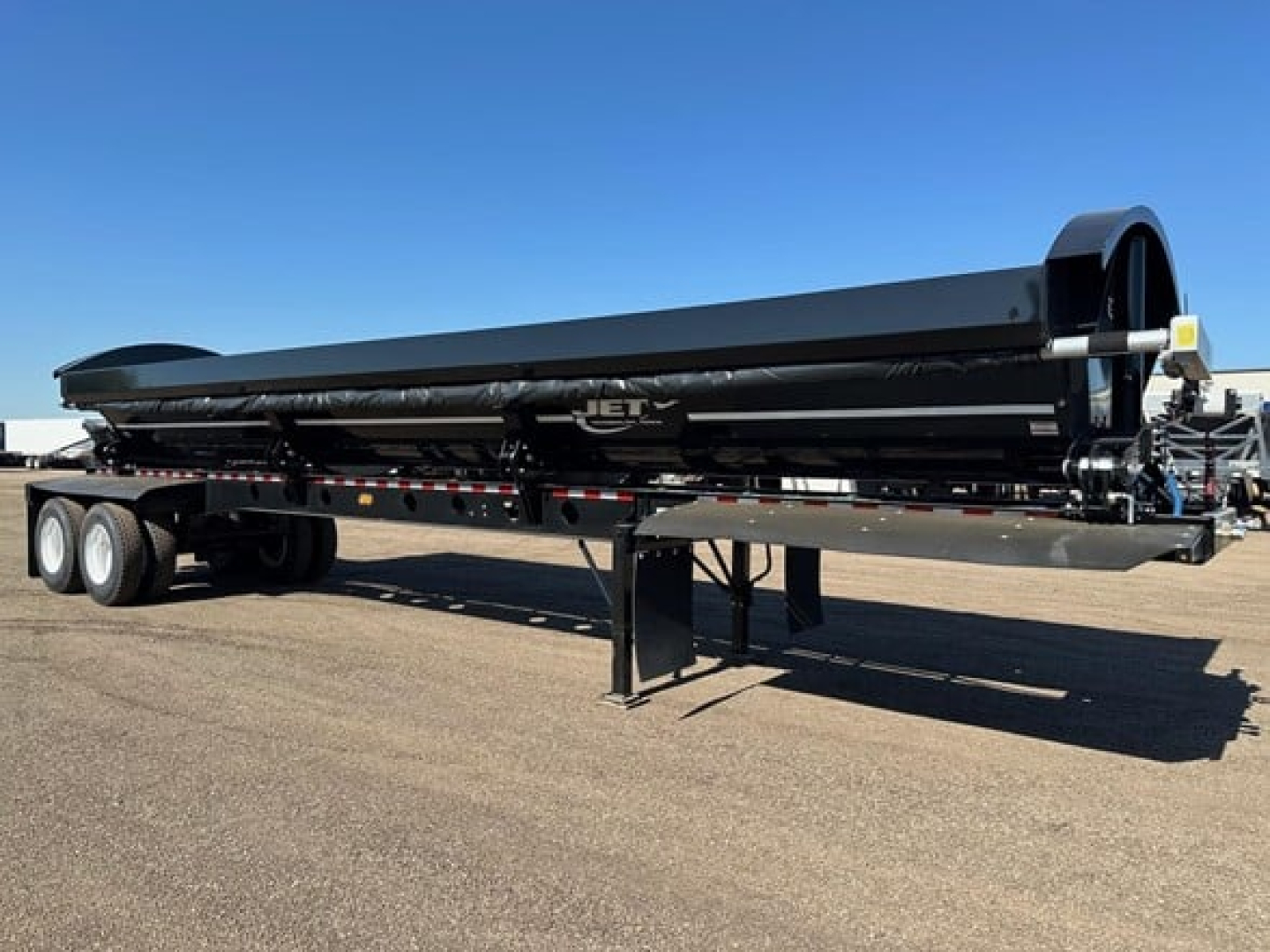 Jet 40' air ride side dump trailer in profile showing black alloy tank, tandem axles, and landing legs with Jet logo visible.