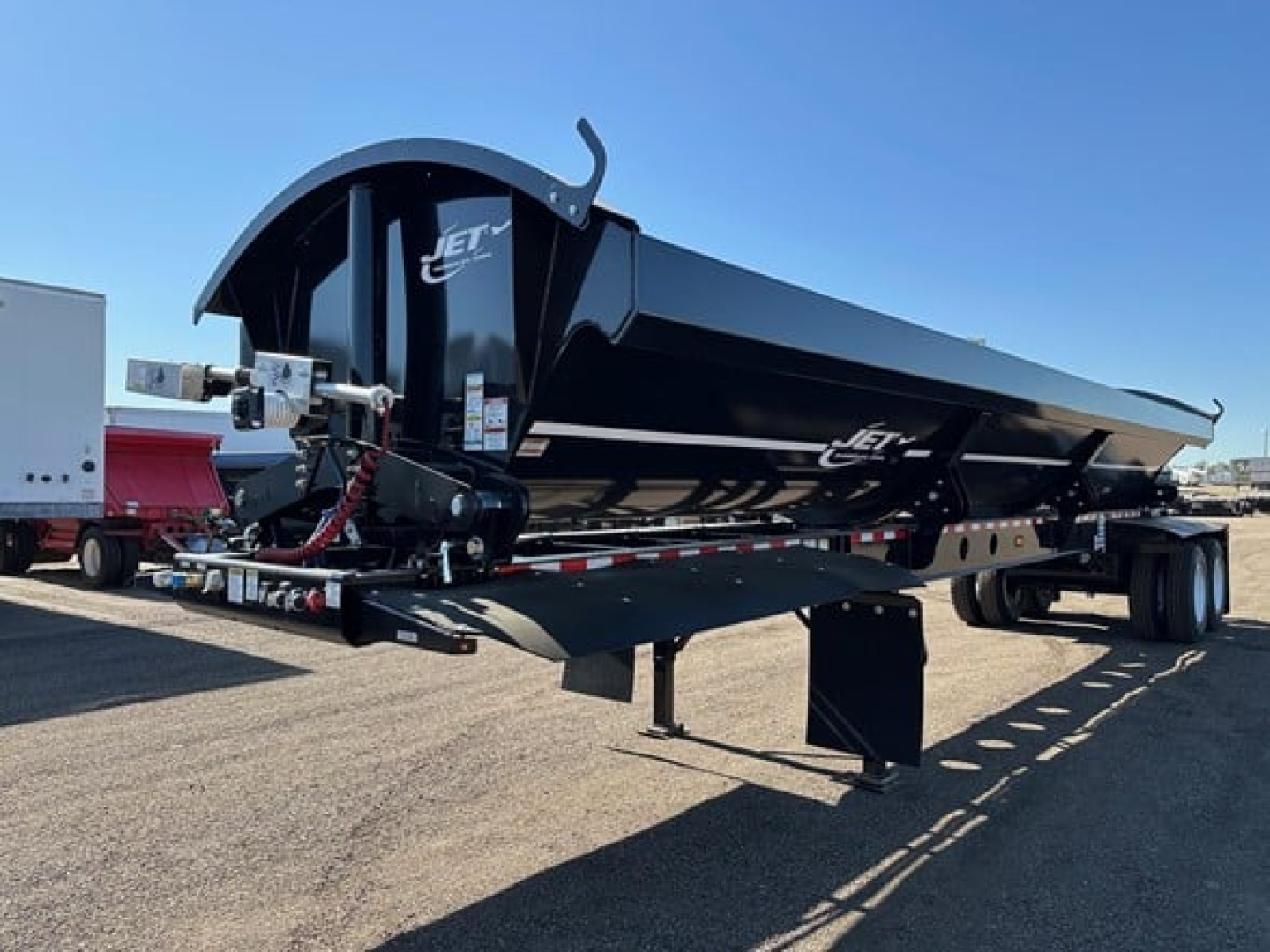 Jet 40' air ride side dump trailer in black with dual rear axles and undercarriage, showing hydraulic system and front hitch. Text on side reads Jet.