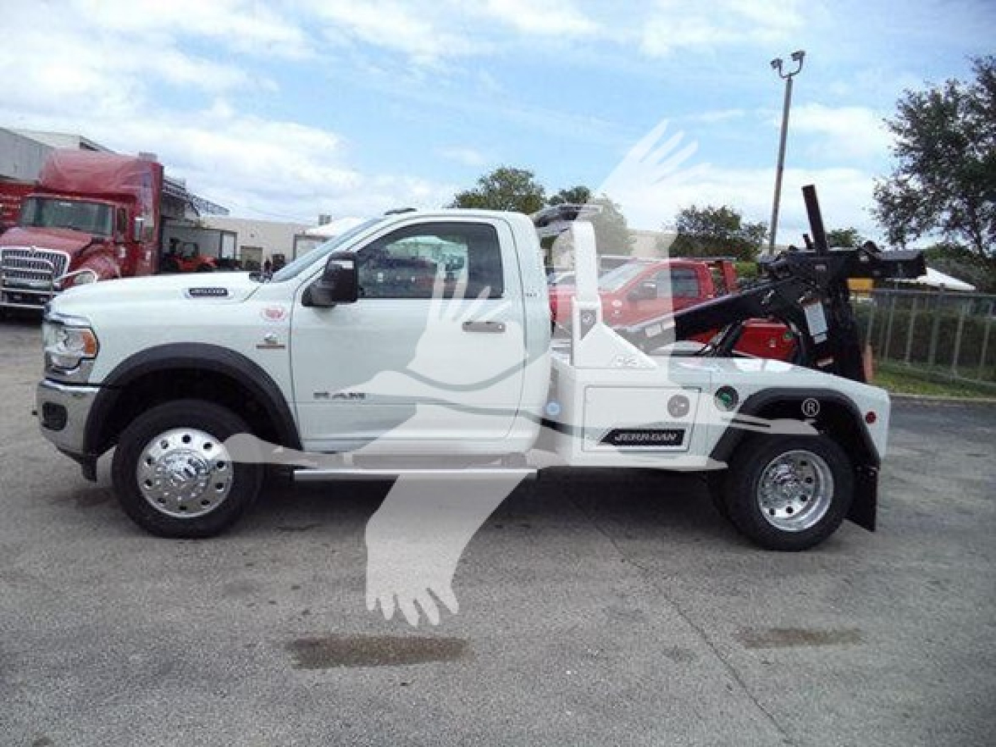 Ram 4500 tow truck with white cab and heavy winch equipment, side view showing front fender badge and wheel details.