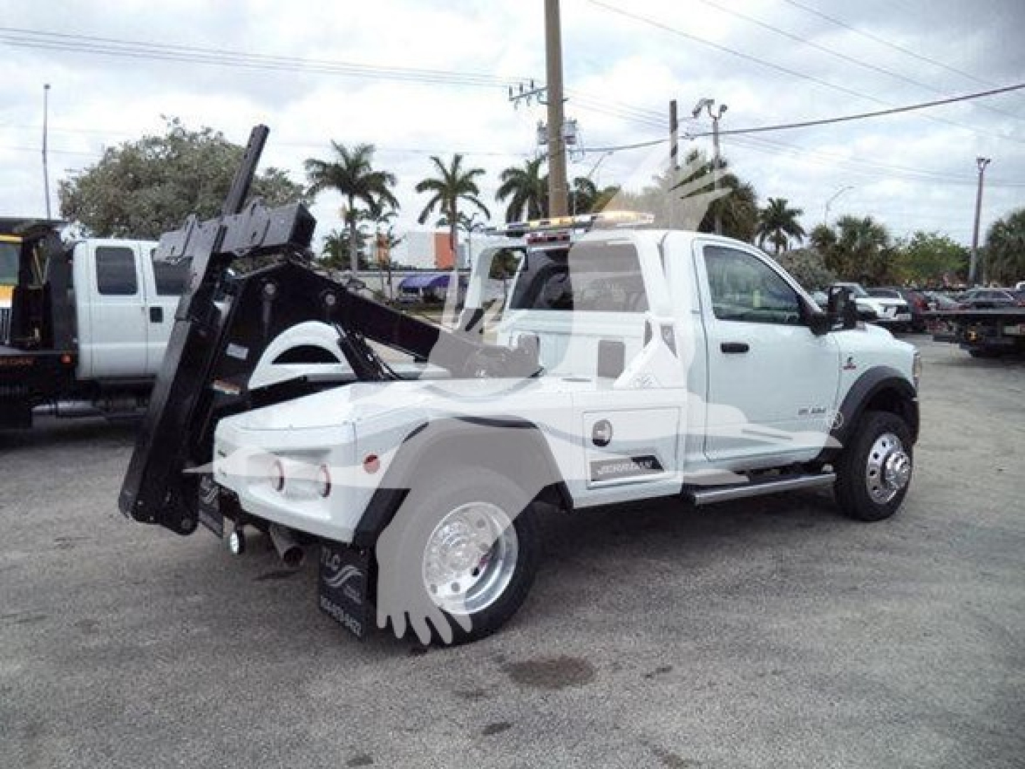Ram 4500 tow truck side view showing wheel-lift equipment and white cab with RAM badge and SLT trim level badge visible.