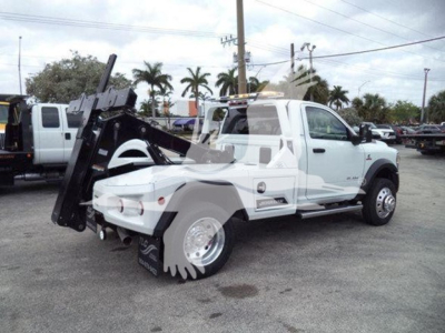 Ram 4500 tow truck side view showing wheel-lift equipment and white cab with RAM badge and SLT trim level badge visible.