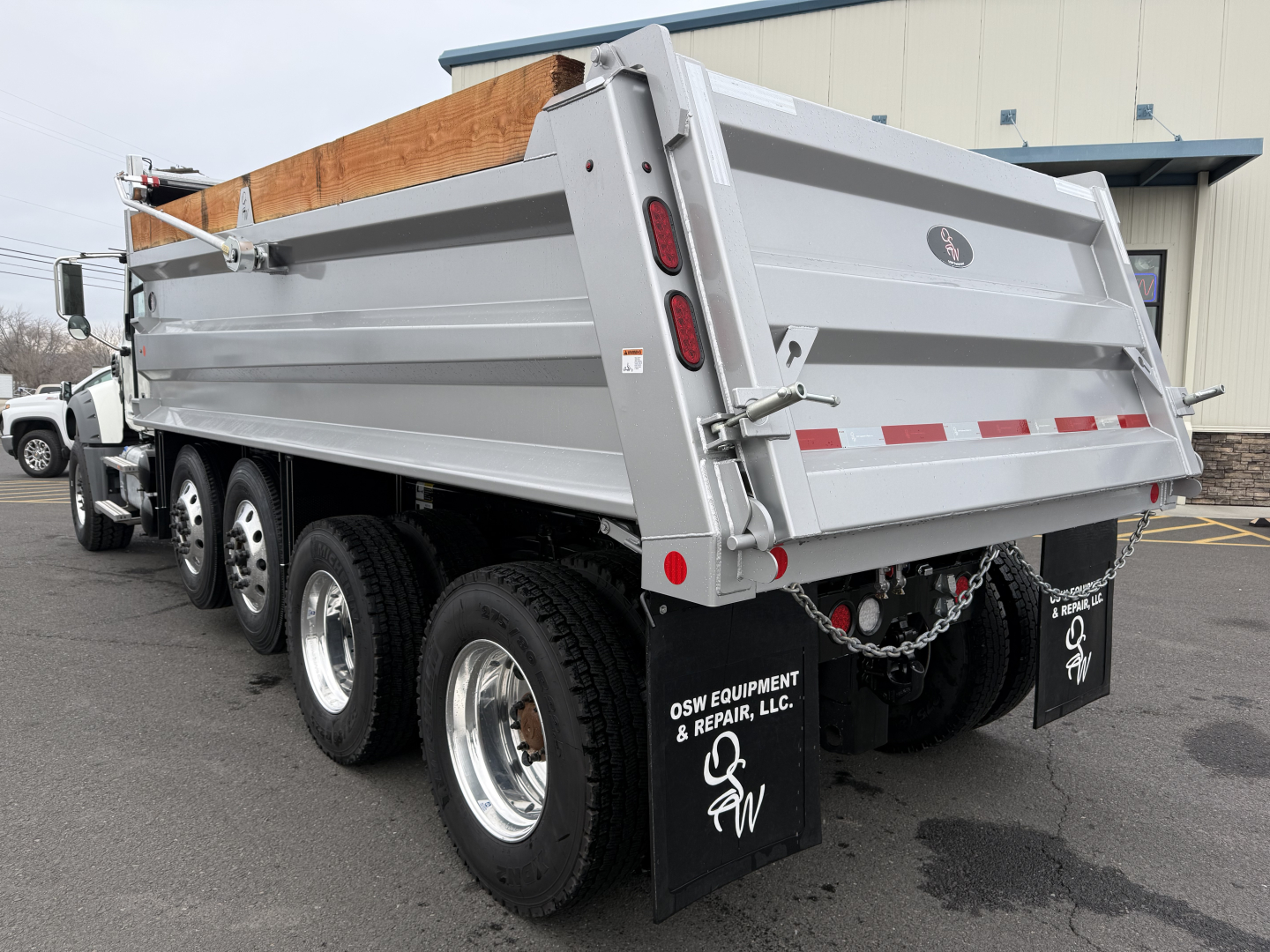 Dump truck bed on a 2025 Mack GR104F showing side panels, rear tailgate, and triple axles with mud flaps.