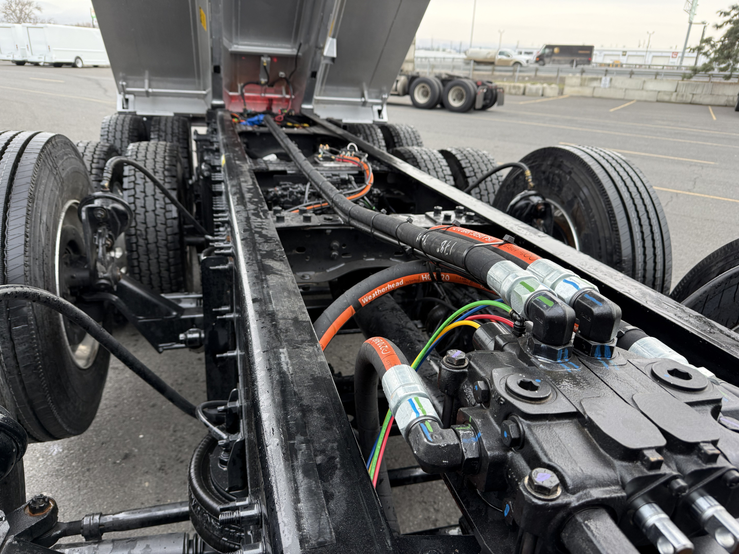 Mack GR104F chassis showing hydraulic lines and control valves, fuel lines, and wiring harness in the truck frame.